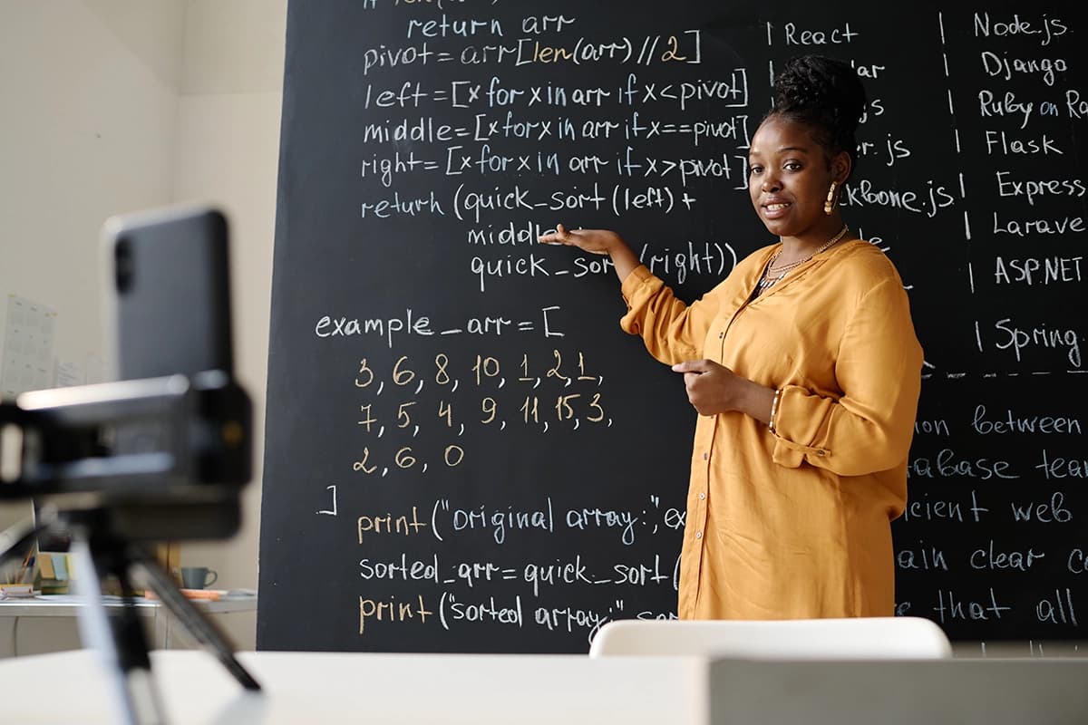 Teacher Explaining Code on Blackboard